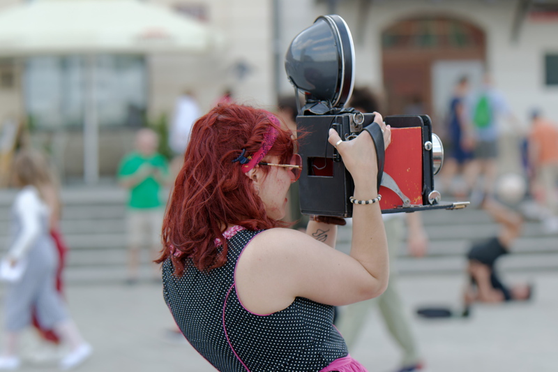 1 - Person using a vintage-style large format camera equipped with a classic flash